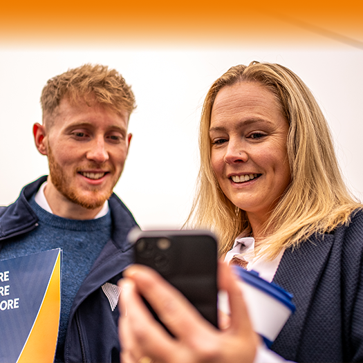 A man and a woman who are looking at a phone and smiling